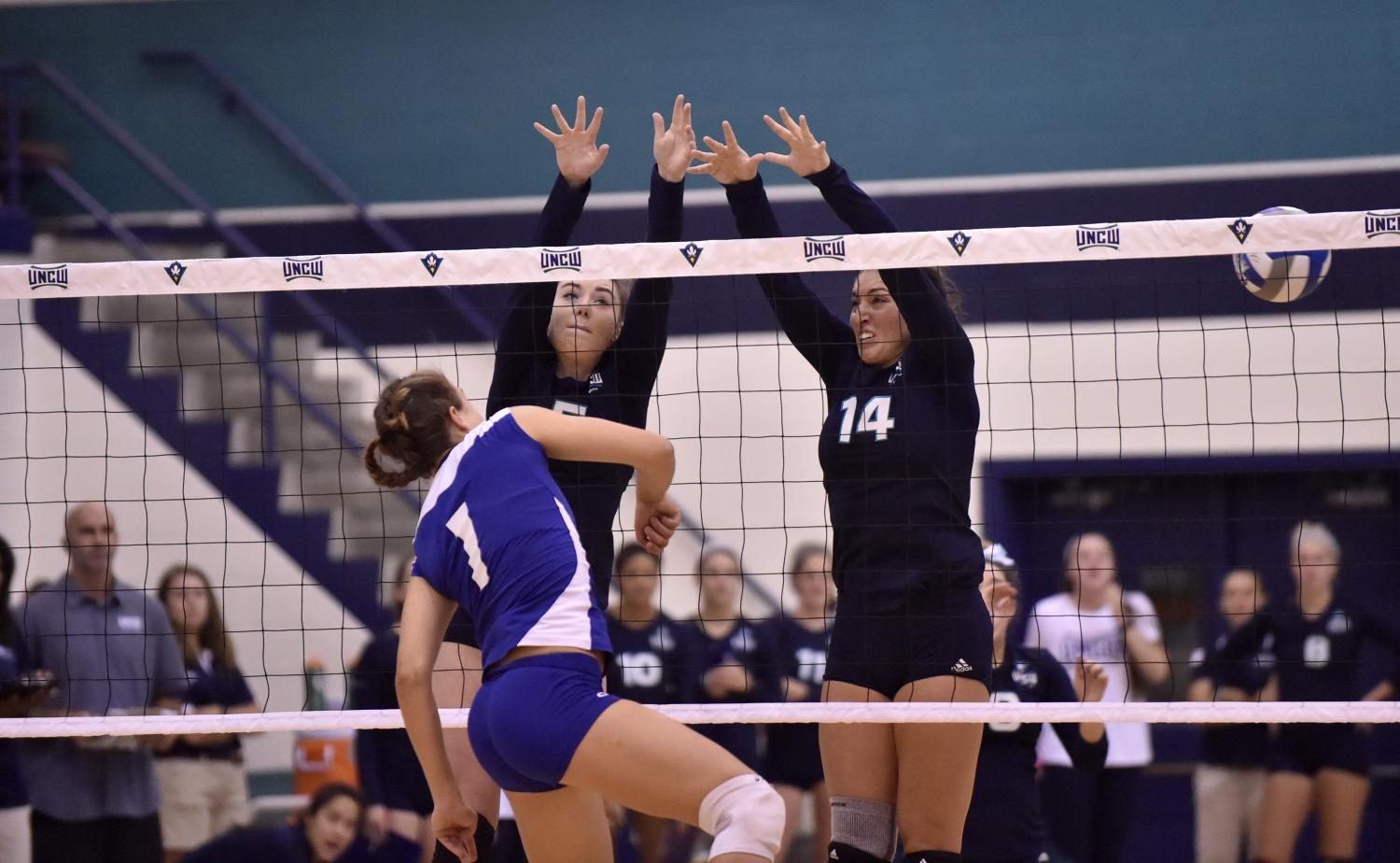 Madison Peters, left, and Sydney Brock, right, block a spike attempt from a Barton player in UNCWs exhibition game vs. Barton College on Aug. 20.