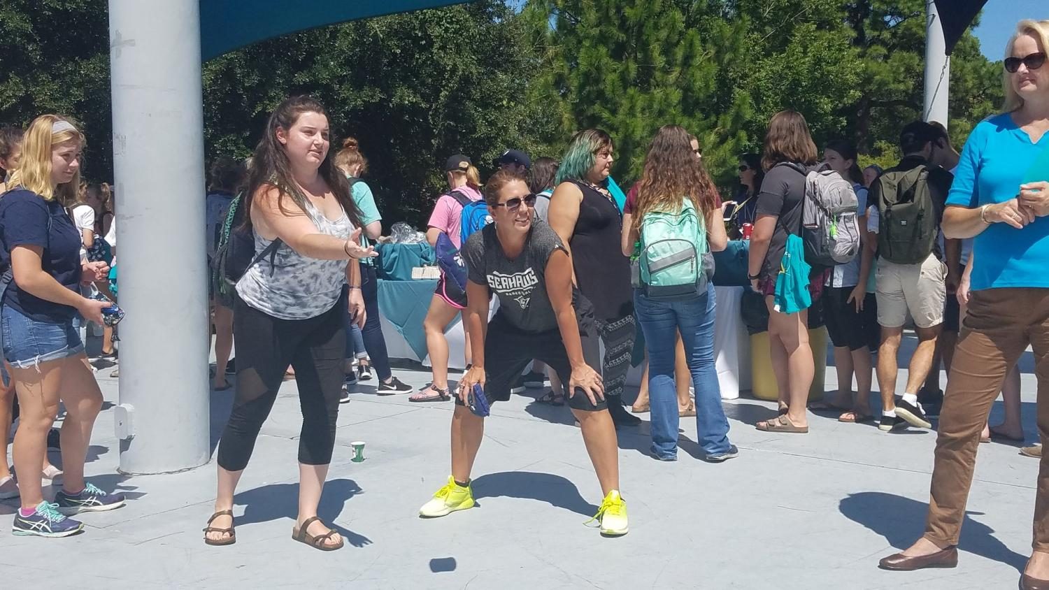 Tiffany Burgess, left, tosses a bean bag during a game of cornhole as UNCW womens basketball coach Karen Barefoot, right, cheers her on during the annual Cookout with the Coaches event on Wednesday, Sept. 13, 2017.