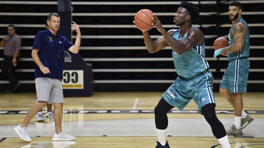 Devontae+Cacok%2C+right%2C+participates+in+drills+while+UNCW+mens+basketball+coach+C.B.+McGrath%2C+left%2C+gives+directions+during+a+preseason+practice.