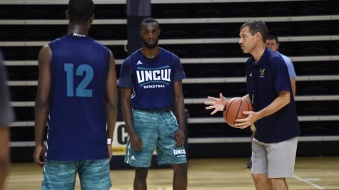 Jay Estime (12) and Ty Taylor, left, take instruction from UNCW men's basketball coach C.B. McGrath during a preseason practice.