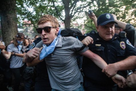 A protestor is led away by police as demonstrators cover the a Confederate statue known as Silent Sam with banners Monday, Aug. 20, 2018 at UNC-Chapel Hill in Chapel Hill, N.C. Demonstrators surrounded and obscured the statue with large banners before toppling it.