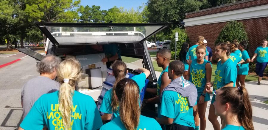 Volunteers swarm a vehicle outside Graham-Hewlett during UNCWs freshman move-in on Saturday, Aug. 18.