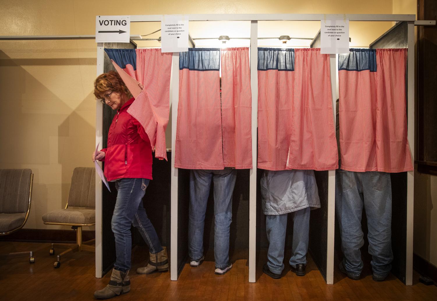 Christine Giroux exits the voting booth at Transit Town Hall Tuesday, Nov. 6, 2018 in Sibley County, Minn. The curtains, an ode the American flag, were sewn by a past election official. (Leila Navidi/Minneapolis Star Tribune/TNS)