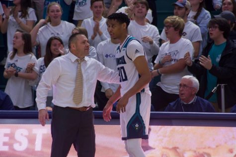 UNCW interim head coach Rob Burke talks to Jaylen Sims on the sideline during the Seahawks' matchup with Hofstra on Jan. 16, 2020