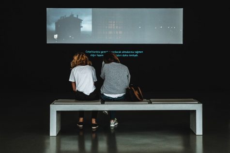 Two women sitting and watching a subtitled film. 