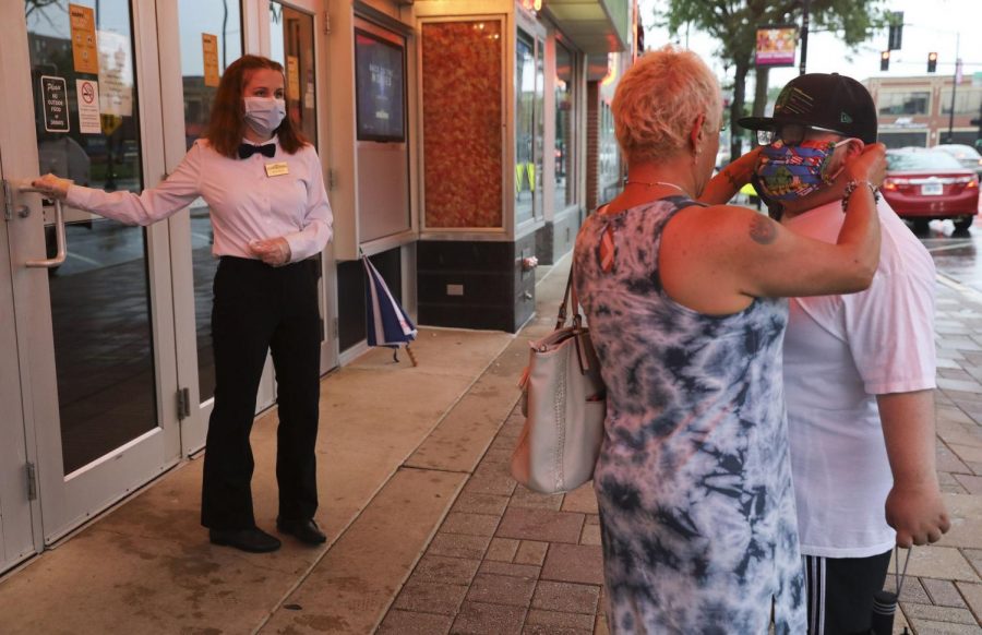 Emerson Becker, 20, holds the door for two customers as they put on their masks before entering Classic Cinemas York Theatre in Elmhurst after reopening on June 26, 2020.

USA