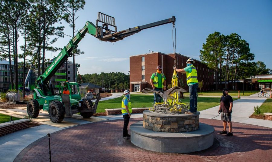 Construction workers and artist Dumay Gorham installing the new seahawk sculpture on campus.  