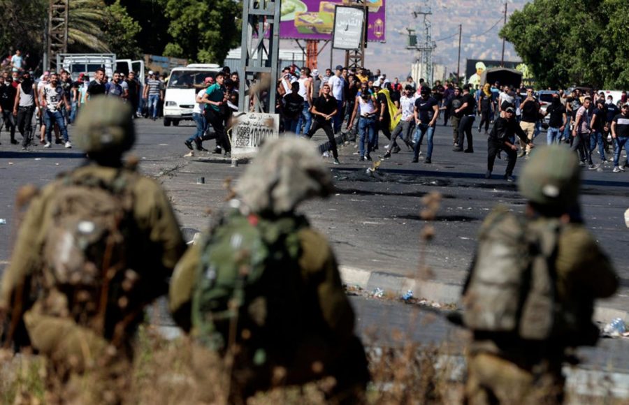 Palestinian protesters clash with Israeli security forces at the Hawara checkpoint south of Nablus city, in the occupied West Bank, on May 18, 2021. - Palestinians across the West Bank and in east Jerusalem and Arab districts in Israel were largely adhering to a general strike called in support of those under bombardment in Gaza, which led to violent clashes throughout the territories. 