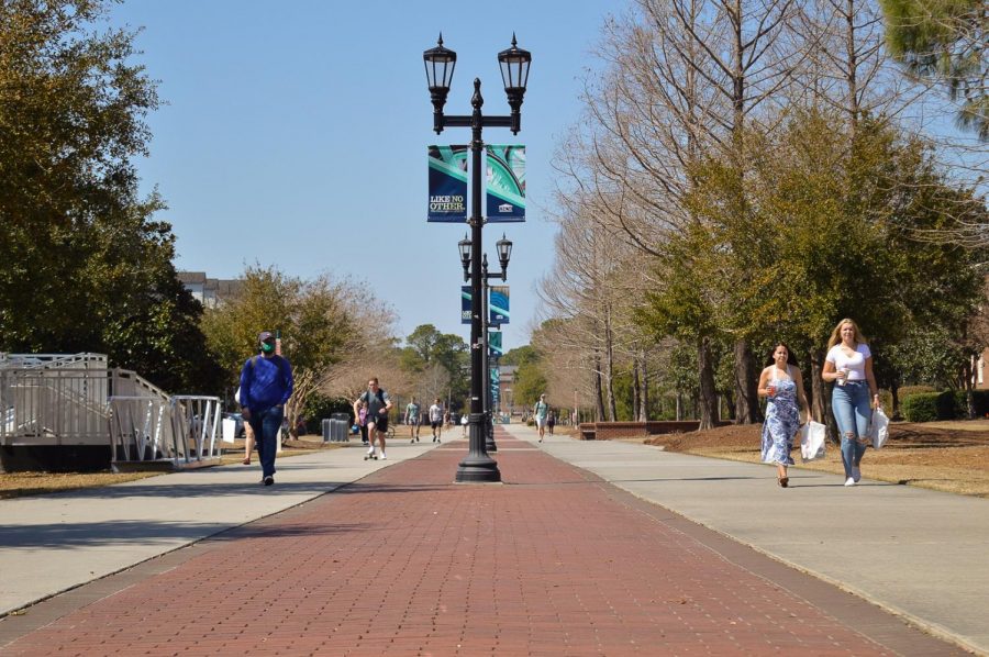 Students walking on campus with and without face masks.