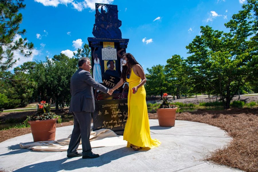 The artist Dare Coulter shakes hands with Chancellor Sartarelli in front of her piece, "Because It's Time."