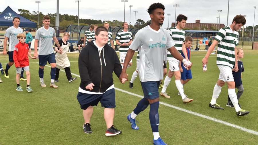 Harry’s Game children walking hand-in-hand with UNCW athletes.