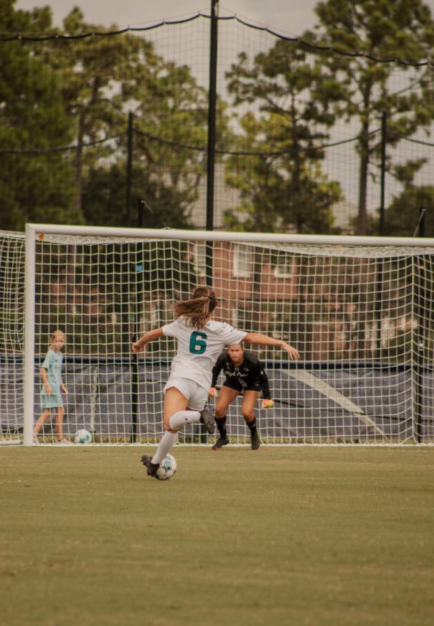 UNCW Womens Soccer player #6 Madison Henry shooting a goal.