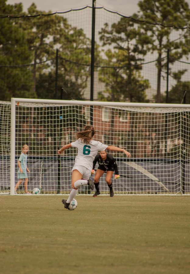 UNCW Women's Soccer player #6 Madison Henry shooting a goal.