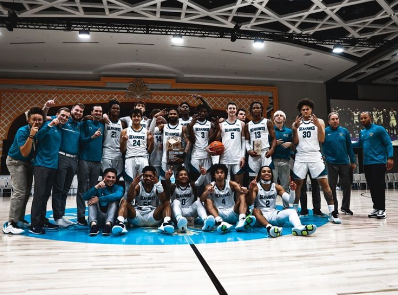 The UNCW men's basketball team posing with their trophy after conquering the 2022 Baha Mar Nassau Championship.