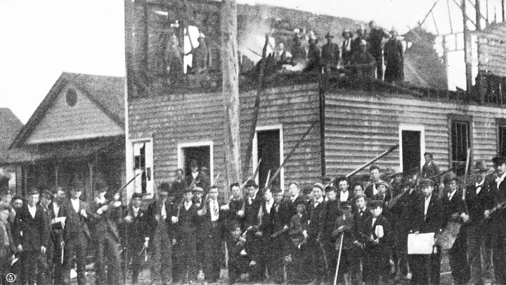 A photo of white supremacists in front of the burned remains of The Daily Record, 1898.