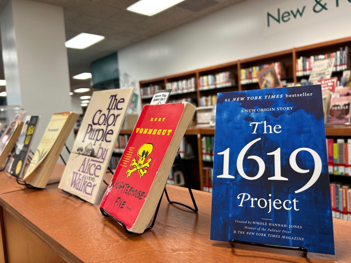 A collection of books that have been banned or challenged across the country. In the foreground is The 1619 Project, which re-examines the influence of slavery in the founding of The United States. The books title references the first reccorded arrival of African slaves to North America in 1619.
