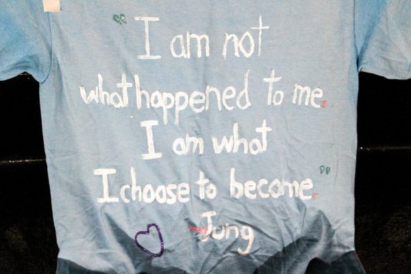 One of more than a dozen shirts hung on the railing of the Campus Commons Amphitheater. Painted on each of them are messages of hope and calls for action against domestic violence.