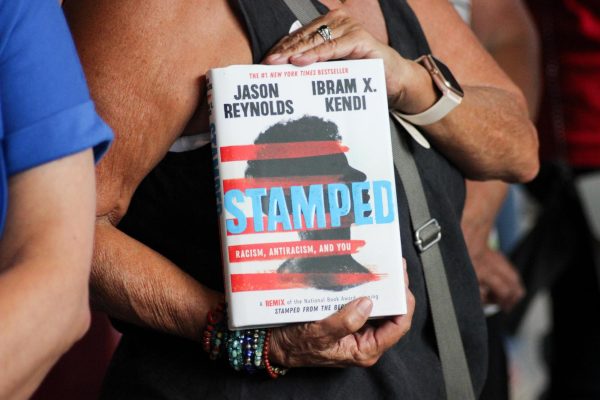 A protestor outside the Board of Education Center holds a copy of “Stamped: Racism, Antiracism, and You during the school boards Aug. 1 meeting.