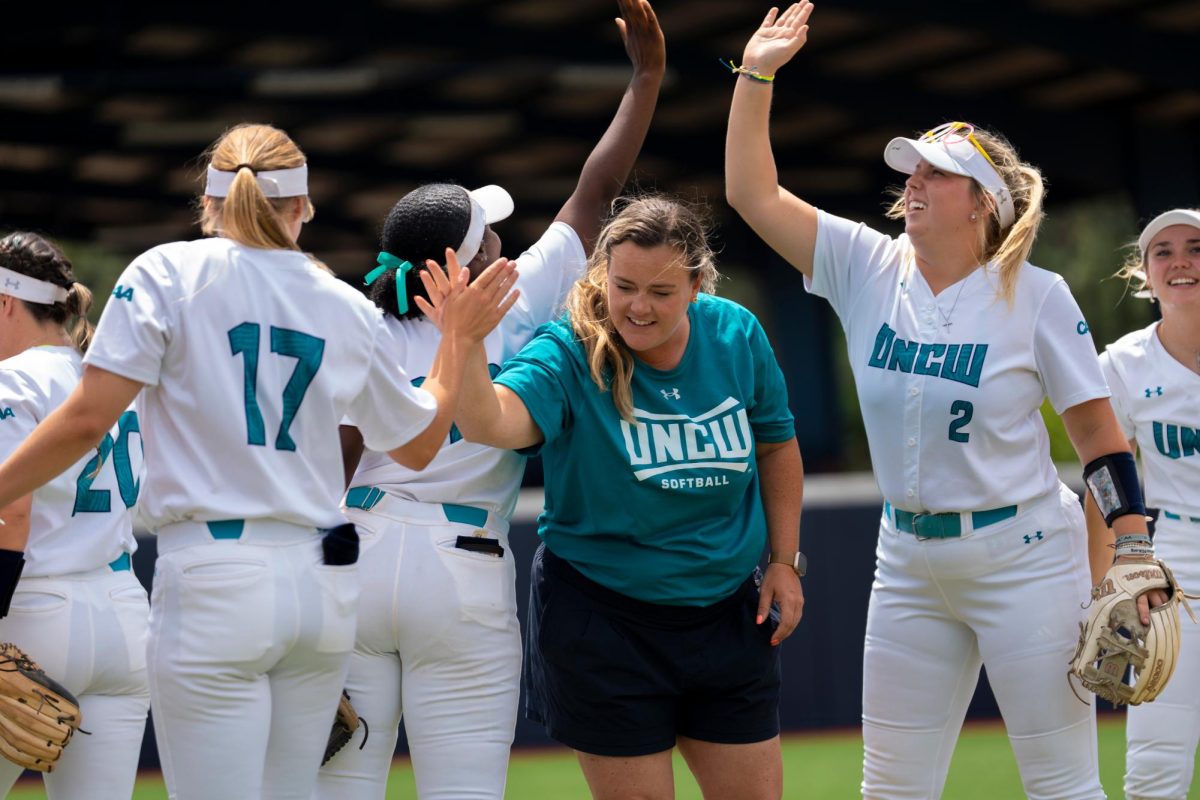Coach Wade high fives and greets several players. (UNCW Athletic Department)