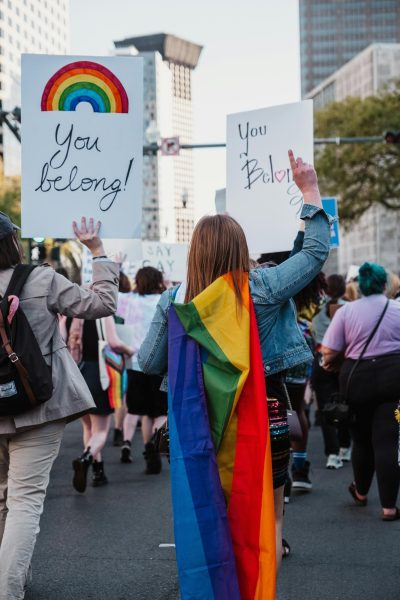 People walk with You belong signs at a Pride month protest. (Adiden Craver/Unsplash.com)