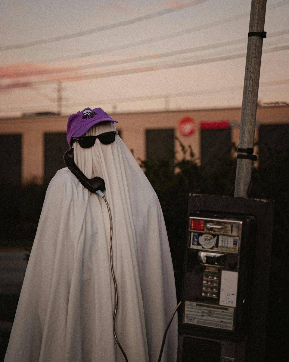 Sheet ghost Halloween costume making a phone call at a phone booth (Courtesy: Dalton Smith/Unsplash). 