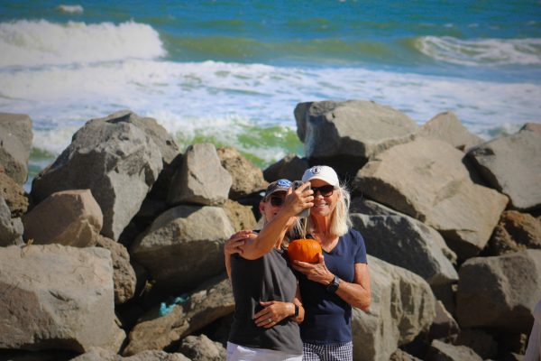 Two women snap a selfie with a pumpkin in front of the ocean (Max Matthews/The Seahawk).